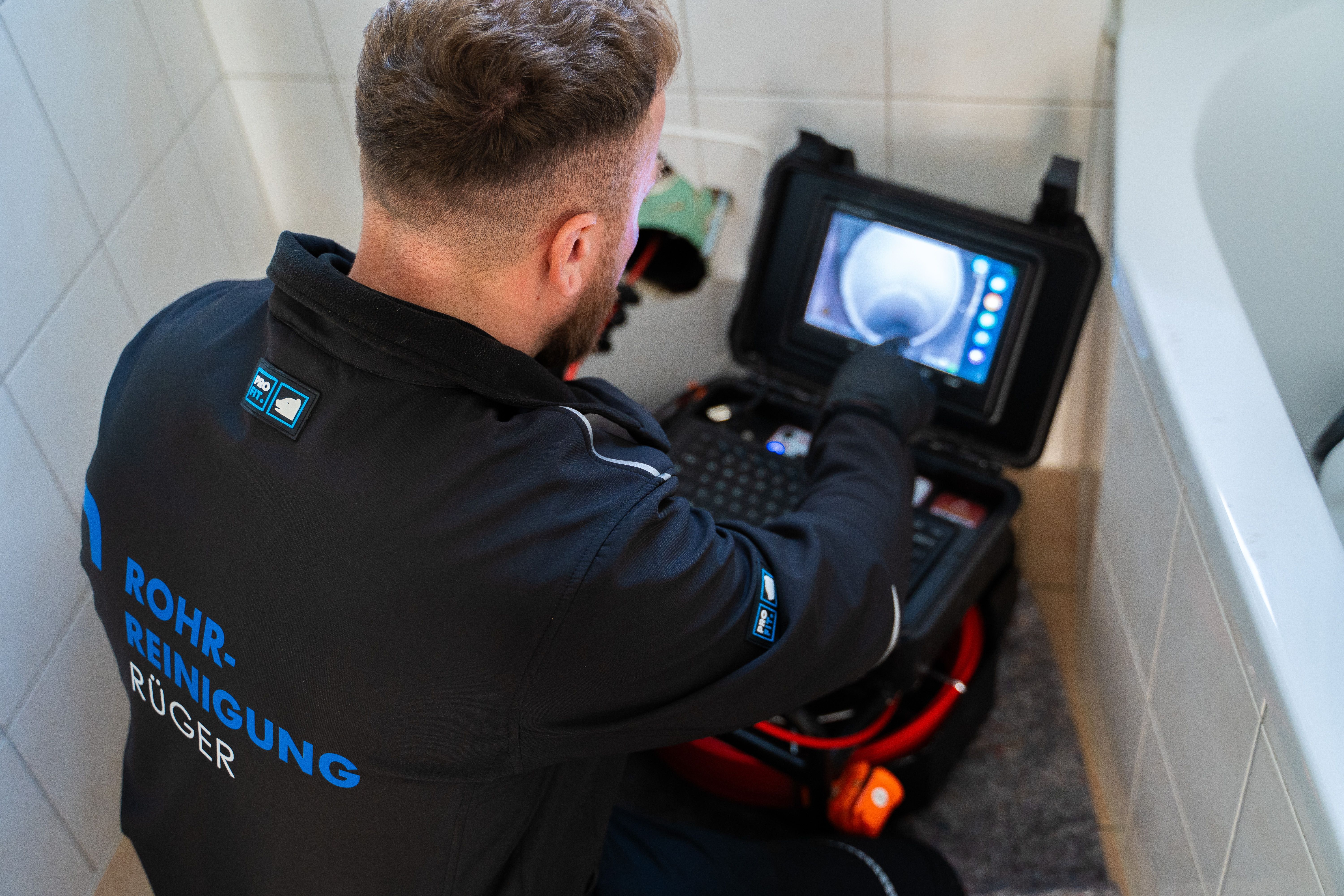 Handwerker prüft ein Rohr mit einer Inspektionskamera und Monitor im Badezimmer