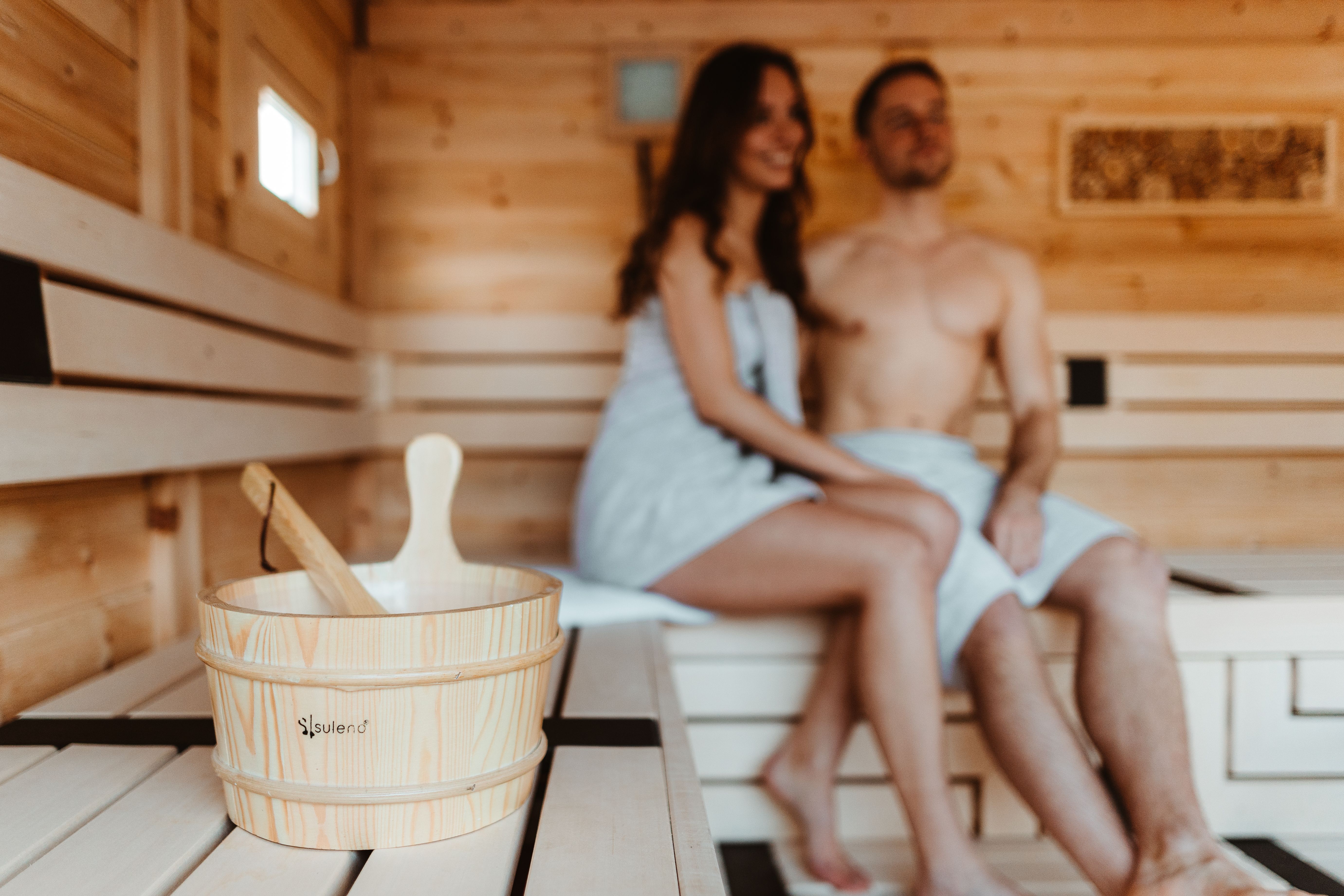 Paar sitzt in einer Holzsauna, warmes Licht