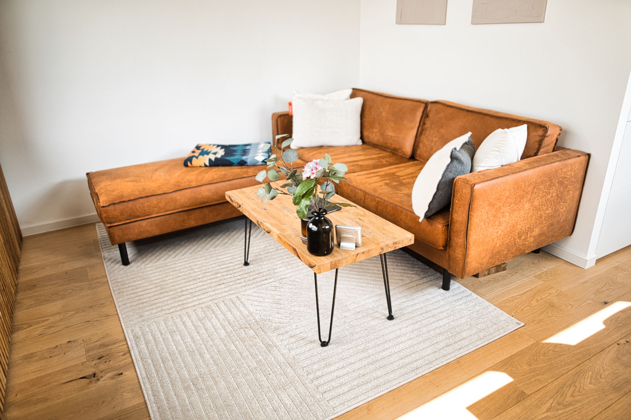 Wohnzimmer mit braunem Ledersofa und Holztisch, helles Tageslicht
