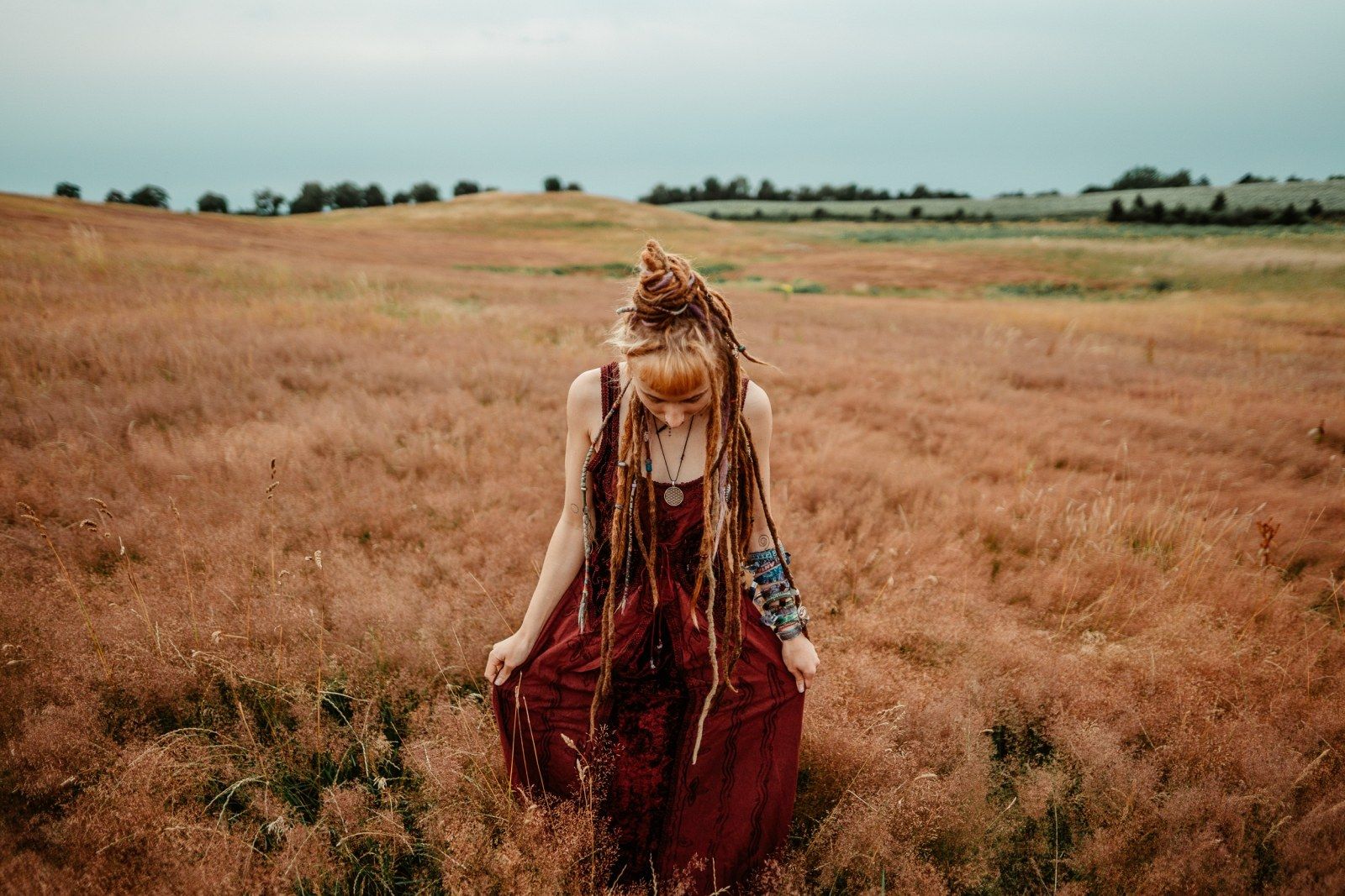 Frau im roten Kleid steht in einem goldenen Feld