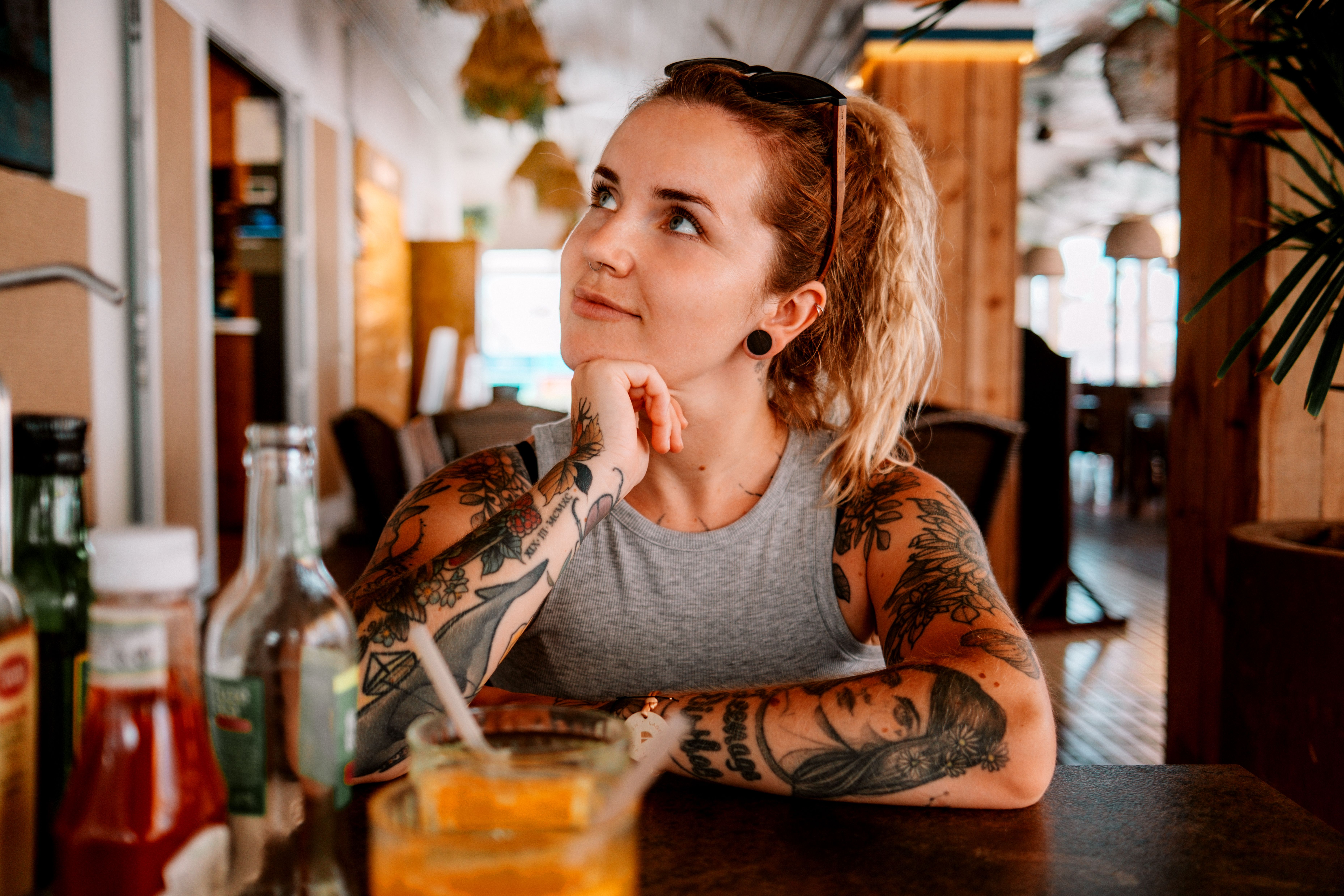 Frau stützt das Kinn auf die Hand und sitzt an einem Tisch in einem Café