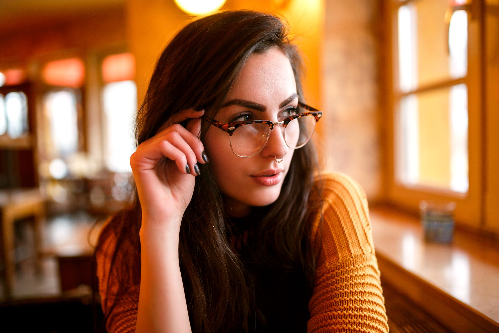 Frau mit Brille am Café-Fenster, warmes goldenes Licht