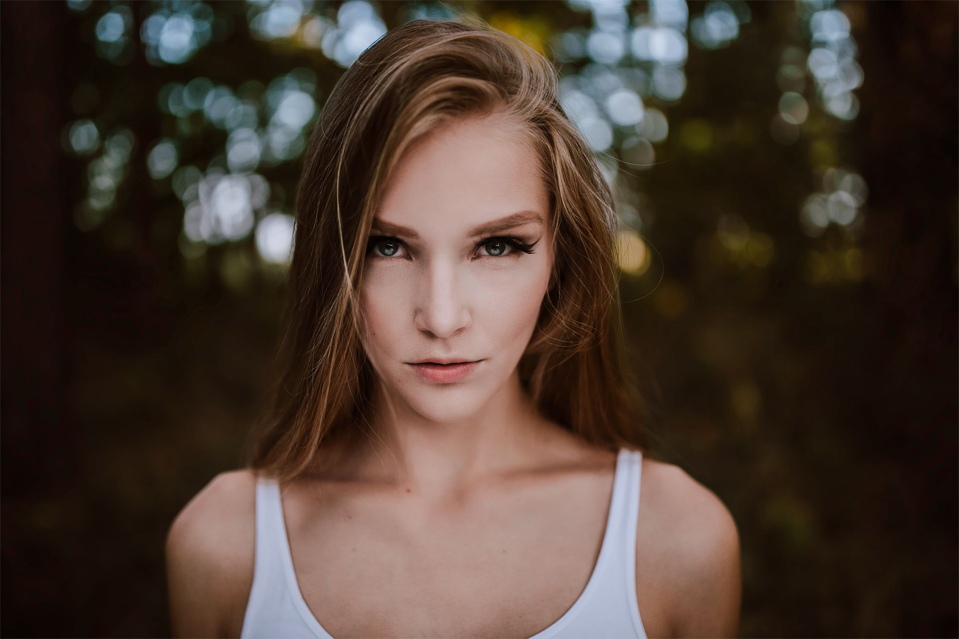 Porträt einer jungen Frau mit direktem Blick vor dunklem Waldhintergrund