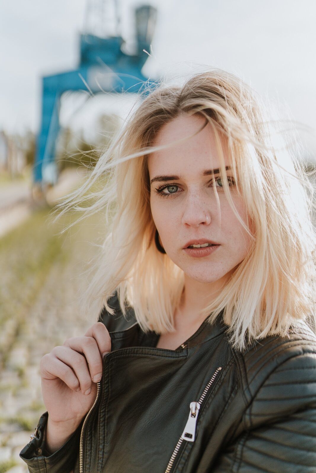 Junge blonde Frau mit wehenden Haaren vor einem Hafenkran