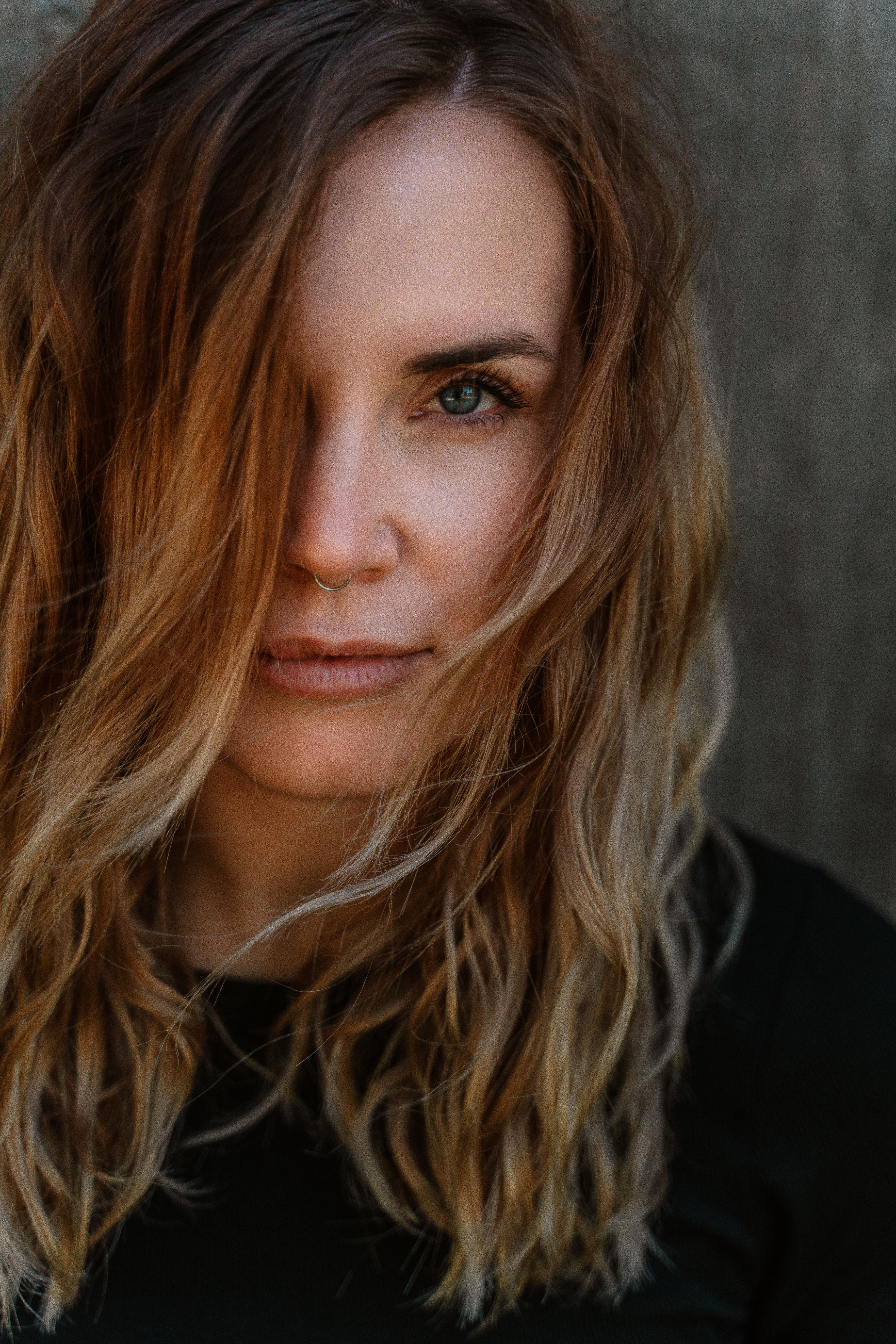 Nahes Porträt einer Frau mit Haarsträhnen im Gesicht, weiches Licht